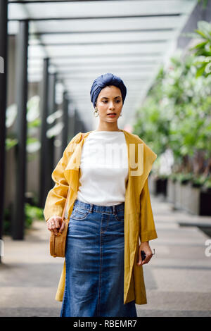 Porträt eines großen, schönen und eleganten im Nahen und Mittleren Osten arabische Frau in einem turban und ein Pastell Outfit stehen auf einer Straße in der Stadt. Stockfoto