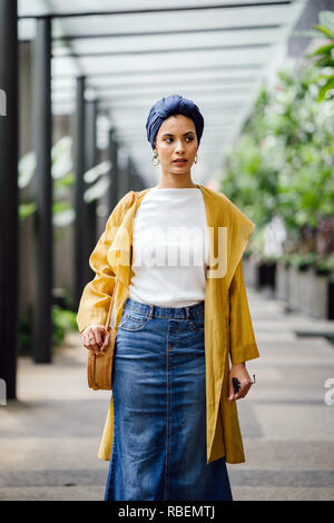 Porträt eines großen, schönen und eleganten im Nahen und Mittleren Osten arabische Frau in einem turban und ein Pastell Outfit stehen auf einer Straße in der Stadt. Stockfoto