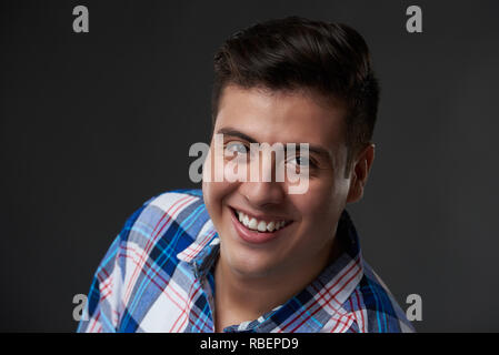 Portrait von Glücklich lächelnde junge Mann im casual Outfit auf Grau studio Hintergrund Stockfoto