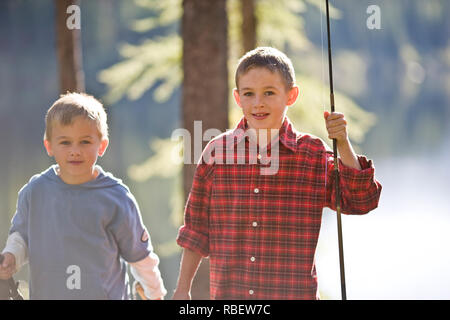 Porträt von zwei jungen Brüder holding Angelruten, während Sie in den Wald. Stockfoto