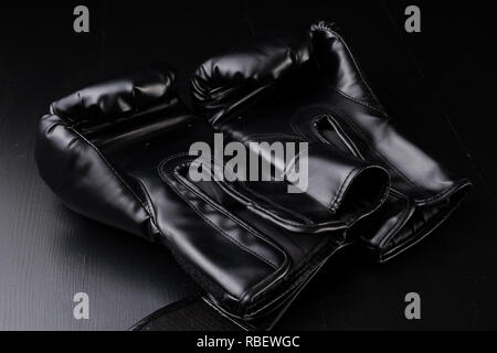 Schwarze Boxhandschuhe auf der Turnhalle Tabelle. Training Zubehör. Der dunkle Hintergrund. Stockfoto