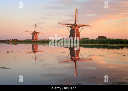 Sommer Sonnenuntergang am Abend in der holländischen Landschaft mit der Reflexion von zwei traditionellen strohgedeckten Windmühlen im Wasser in Leidschendam, Niederlande Stockfoto