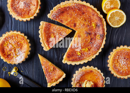 Traditionelle Schweizer Ostern Dessert - Reis Torten bestreut mit Puderzucker und der Zitronenschale, Torte de Paques, Osterfladen, auf einem Schwarzen Tisch mit Zitrone Stockfoto