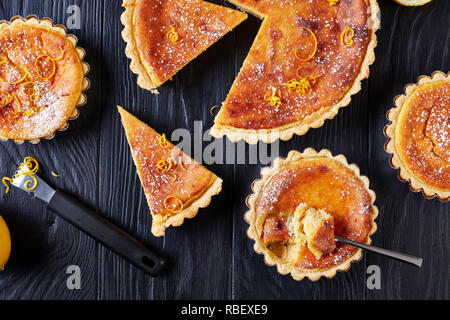 Schweizer Ostern Dessert - Reis Kuchen mit Puderzucker und der Zitronenschale bestreut, Torte de Paques, Osterfladen, auf einem Schwarzen Tisch mit Zitrone Stockfoto