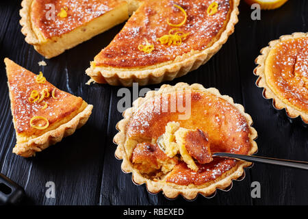 Schweizer Ostern Dessert - Reis Kuchen mit Puderzucker und der Zitronenschale bestreut, Torte de Paques, Osterfladen, auf einem Schwarzen Tisch mit Zitrone, horizontal Stockfoto