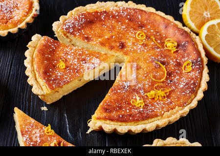 Schweizer Ostern Dessert - griess Kuchen mit Puderzucker und der Zitronenschale in Scheiben geschnitten sprengte, Torte de Paques, Osterfladen, auf einem Schwarzen Tisch mit Stockfoto