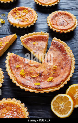 Schweizer Ostern Dessert - griess Kuchen mit Puderzucker und der Zitronenschale in Scheiben geschnitten sprengte, Torte de Paques, Osterfladen, auf einem Schwarzen Tisch mit Stockfoto