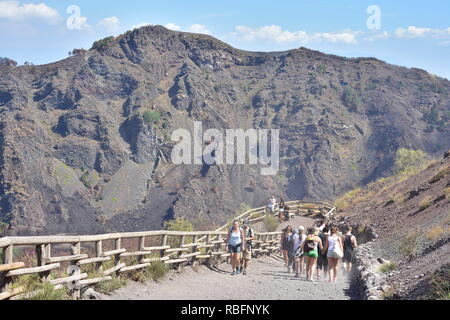 Gruppe der Touristen zu Fuß bis staubigen Weg mit Holzgeländer zum Gipfel des Vesuv auf heißen Sommertag. Stockfoto