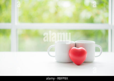 Zwei weiße Tasse Kaffee mit lheart Form auf weiße Holztisch. Grüne Blätter von Farnen als Hintergrund. Ausgaben, freie Zeit für Konzept entspannen. Stockfoto