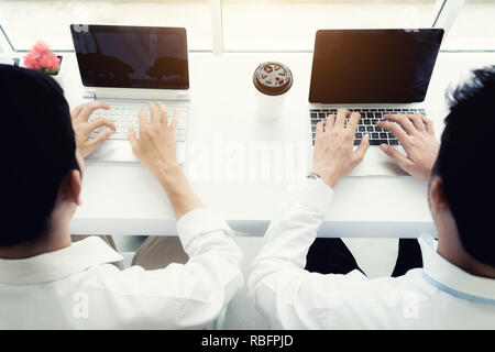 Zwei Freunde business Mann sitzt im Cafe und trinken Kaffee. Blick von oben auf die beiden Kollegen Geschäftsleute arbeiten mit Laptop im Coffee Shop. Stockfoto