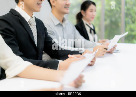 Fröhliche business Mann sitzt mit anderen Profis warten auf Job Interview. Gruppe von Menschen warten auf Job Interview im Büro Stockfoto