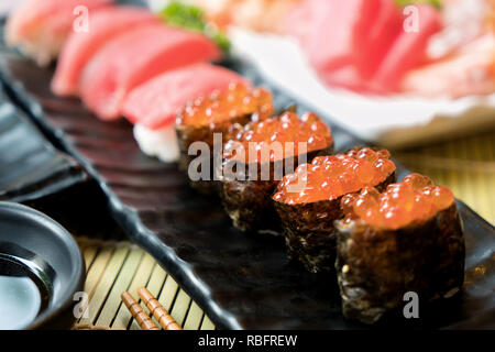 Sushi mit Stäbchen und Sojasauce. Sushi Roll japanisches Essen im Restaurant. Lachs Rogen Sushi mit Lachs, Gemüse, fliegender Fischrogen und Kaviar Stockfoto