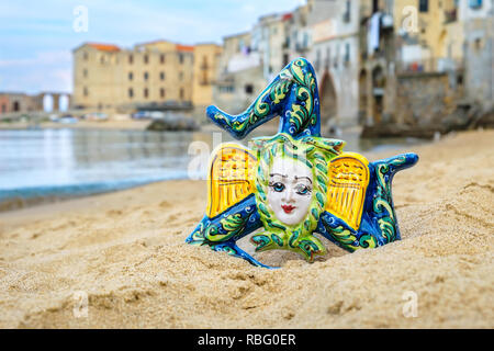 Traditionelles sizilianisches Souvenir - Keramik Trinacria an einem Sandstrand in Cefalu. Sizilien, Italien Stockfoto