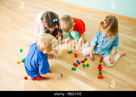 Süße Kinder sammeln Spielzeug in transparetnt Box aus Kunststoff nach dem Spielen im Kindergarten. Kinder sie Spielzeug, um nach dem Spiel an der Waldorfschule. Zu Stockfoto