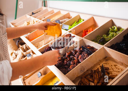 Die Frau ist die Verpackung getrocknet aprisots im Lebensmittelgeschäft. Getrocknete Früchte in die Holzkisten, veganes Essen Stockfoto