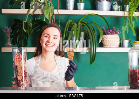 Junge Lächeln Frau zeigt die Entwässerte raw vegan trockenem Brot auf den Showcase in vegan Shop Stockfoto