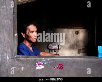 ANTIPOLO, Rizal, Philippinen - Januar 2, 2019: Ein erwachsener Mann im Rollstuhl sitzt am Fenster seines Hauses. Stockfoto