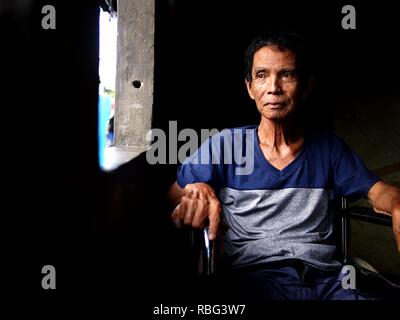 ANTIPOLO, Rizal, Philippinen - Januar 2, 2019: Ein erwachsener Mann im Rollstuhl sitzt am Fenster seines Hauses. Stockfoto