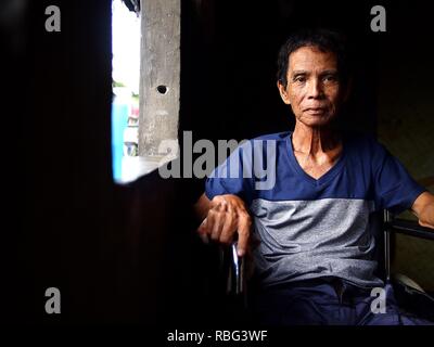 ANTIPOLO, Rizal, Philippinen - Januar 2, 2019: Ein erwachsener Mann im Rollstuhl sitzt am Fenster seines Hauses. Stockfoto