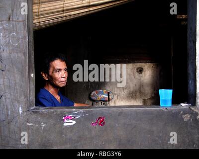 ANTIPOLO, Rizal, Philippinen - Januar 2, 2019: Ein erwachsener Mann im Rollstuhl sitzt am Fenster seines Hauses. Stockfoto