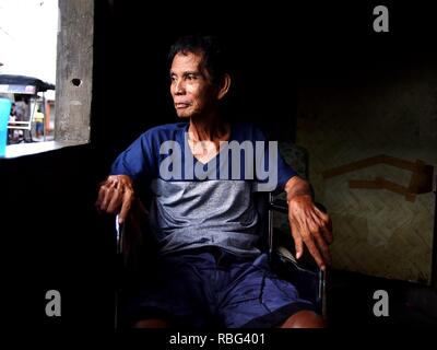 ANTIPOLO, Rizal, Philippinen - Januar 2, 2019: Ein erwachsener Mann im Rollstuhl sitzt am Fenster seines Hauses. Stockfoto