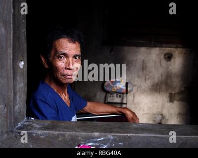 ANTIPOLO, Rizal, Philippinen - Januar 2, 2019: Ein erwachsener Mann im Rollstuhl sitzt am Fenster seines Hauses. Stockfoto