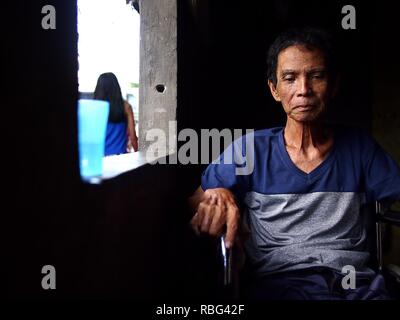 ANTIPOLO, Rizal, Philippinen - Januar 2, 2019: Ein erwachsener Mann im Rollstuhl sitzt am Fenster seines Hauses. Stockfoto