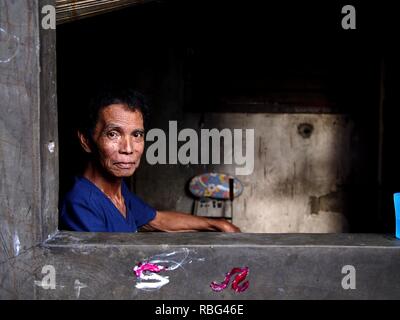 ANTIPOLO, Rizal, Philippinen - Januar 2, 2019: Ein erwachsener Mann im Rollstuhl sitzt am Fenster seines Hauses. Stockfoto