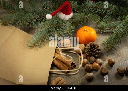 Verschiedene Nüsse, Zimt und Clementine als Konzept der Urlaub Lebensmittel, auf hölzernen Tisch aus Papier Shopping Bag verbreiten, in enger gesehen - von hoher Stockfoto