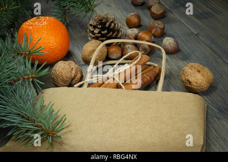 Verschiedene Nüsse, Zimt und Clementine als Konzept der Urlaub Lebensmittel, auf hölzernen Tisch aus Papier Shopping Bag verbreiten, in enger gesehen - von hoher Stockfoto