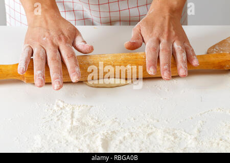 Frau rollt heraus Rohe frische Teig mit Rolling Pin Stockfoto