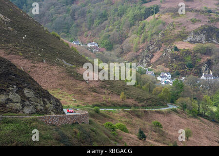 Die Sychnant Pass in der Nähe Conwy in Nordwales. Blick hinunter auf das Dorf Capelulo. Ein rotes Auto auf der Straße. Stockfoto