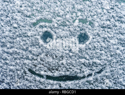 Ein glückliches Gesicht gezeichnet auf einem schneebedeckten Windschutzscheibe. Stockfoto