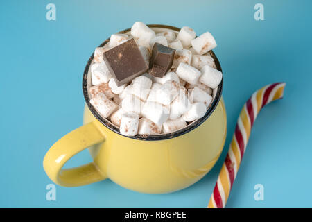 Tasse heiße Schokolade mit Marshmallows auf und halten einen Lutscher auf einem blauen Hintergrund. Gemütliche warme Winter Karte Stockfoto