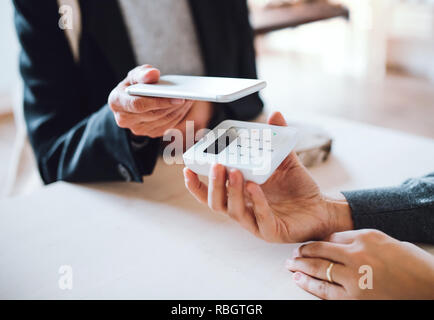 Ein Mittelteil von Kunde und Verkäufer, mobile Zahlung in einem Shop. Stockfoto