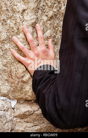 Eine Hand berührt die Klagemauer in der Kotel während ein Gebet von einem anonymen Mann in der Altstadt von Jerusalem. Stockfoto