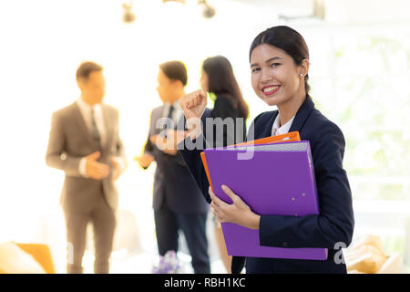 Portrait von asiatischen Geschäftsfrau halten Arbeitsdatei mit Business Team im Hintergrund für coporate Hintergrund arbeiten Stockfoto