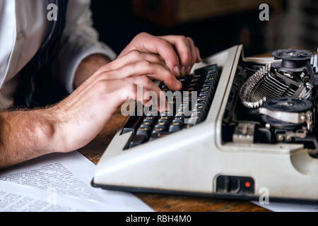 Die Hände des jungen Mannes Eingabe neues Buch auf einem antiken vintage Schreibmaschine, Erntegut anzeigen Stockfoto