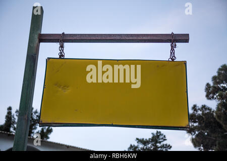 Leeren Alten verwitterten Straße Name Schilder hängen von rostige Kette und Metallstange Horizontal. Closeup Angle Shot von Overhead Straßenschild Platte unter Blau Stockfoto