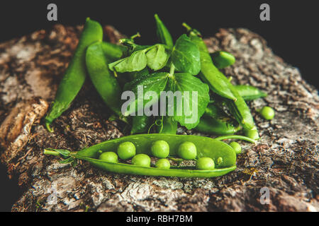 Grüne Erbsen in Hülsen auf einer hölzernen Oberfläche. Rustikal. Stockfoto