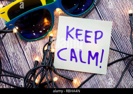 Zerstreut Beleuchtete winzige LED Stringlight auf Holz- Oberfläche. Zwei bunte Sonnenbrille mit Licht widerspiegelt. Schriftliche Meldung erinnern, Ruhe zu bewahren. Stockfoto