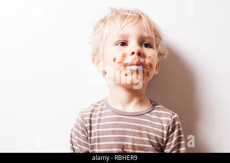 Junge eated Schokolade, lustige schmutzig lächelte Gesicht Stockfoto