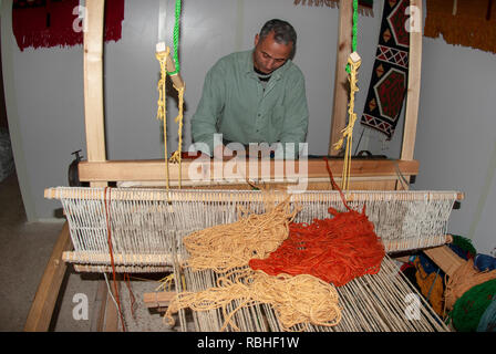 Hand webt einen wollenen Teppich auf dem Webstuhl zu einem Kunsthandwerksladen in Madaba Jordanien Stockfoto