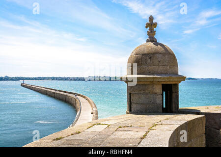 Der wellenbrecher in der Altstadt von Saint-Malo in der Bretagne, bei Flut von der Stadtmauer an einem sonnigen Tag gesehen, mit einem Stein Revolver im Vordergrund. Stockfoto