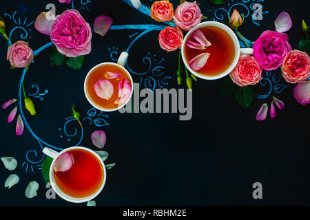 Teetassen und Blütenblätter in Chalk Baum flach. Rose Kaffee creative flach auf einem dunklen Hintergrund mit Kopie Raum Stockfoto