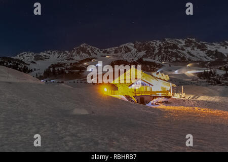 Beleuchtete Chalet am Abend mit Schneekanonen auf dem Hintergrund der Vorbereitung der Skipisten, Passo San Pellegrino, Dolomiten, Italien Stockfoto