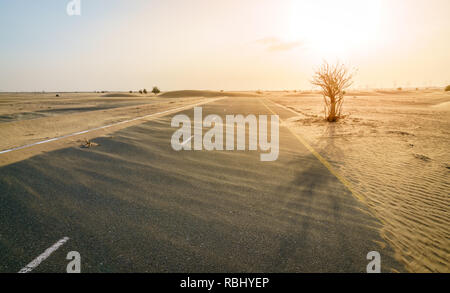 Sand ist das Übernehmen einer Wüste Straße in der Nähe von Dubai in den Vereinigten Arabischen Emiraten. Stockfoto