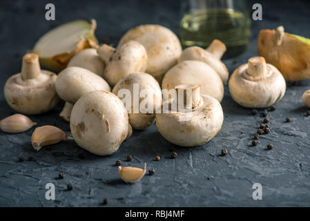 Frische weiße Champions, Gewürze und Zutaten auf der dunklen Küche Tisch. Das Konzept der Küche Pilzgerichte Stockfoto