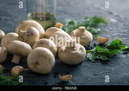 Frische weiße Champions, Gewürze und Zutaten auf der dunklen Küche Tisch. Das Konzept der Küche Pilzgerichte Stockfoto