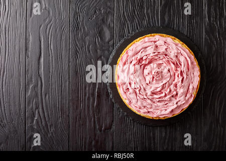 Raspberry cheesecake gekrönt mit Frischkäse gefärbt mit Boden Himbeeren auf einen schwarzen Stein Fach auf Holztisch, flatlay, kopieren Raum Stockfoto